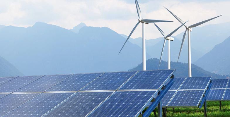 solar panels and wind turbines against mountains